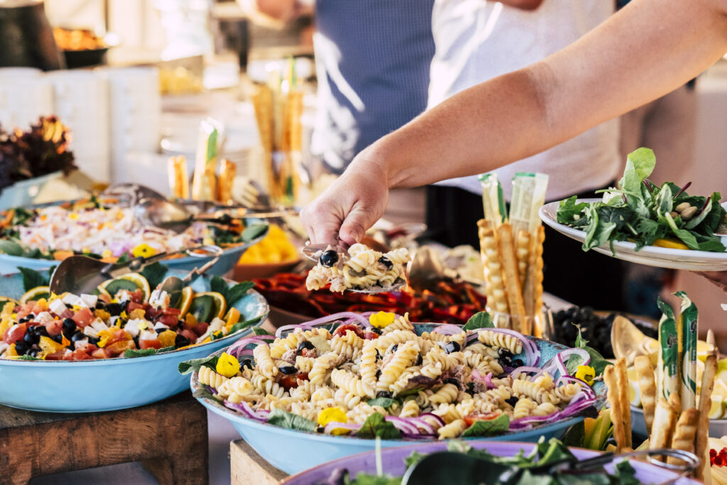 close up of view of table full of food with someone taking pasta of the table to celebrate
